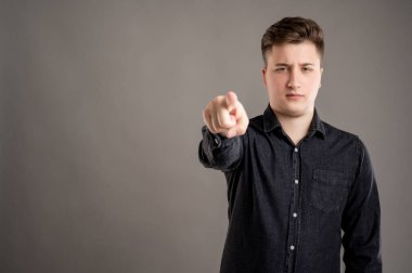 Gri arka planda, fotokopi alanı reklam alanı ile izole edilmiş siyah gömlekli ciddi ve şık çekici bir adamın portresi.