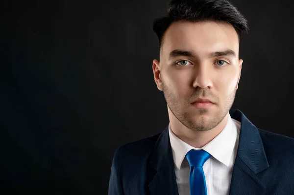 Close-up portrait of business man wearing blue business suit and tie isolated on black background with copy space advertising area