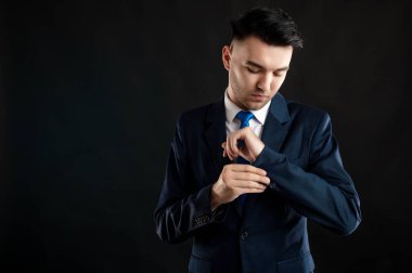 Ceketinin kollarını düzenleyen iş adamının portresi siyah arka planda fotokopi alanı reklam alanı ile izole edilmiş.