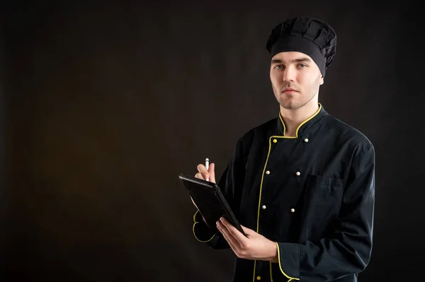 Portrét Mladého Muže Oblečeného Černém Kuchařském Obleku Dělá Poznámky Dívá — Stock fotografie