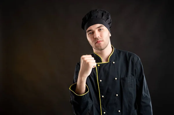Portret Młodego Mężczyzny Ubranego Czarny Kombinezon Kucharski Pokazujący Pięść Pozującą — Zdjęcie stockowe