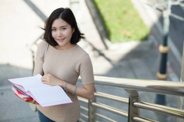 Güzel Asyalı kadın üniversite öğrencisi lise programı akıllı genç kavram öğrenme insanlar eğitim kitaplarını gülümseyerek mutlu bir şekilde açık, ayakta tutan