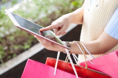 Dijital tablet shoopping online ile birçok renk çanta kullanan genç kadın