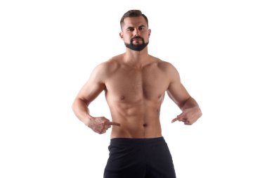 Güçlü bir gövde ile Atlet midesindeki küpler üzerinde parmakları gösterir. Kaslı adam beyaz arka plan üzerinde izole onun abs gösterir