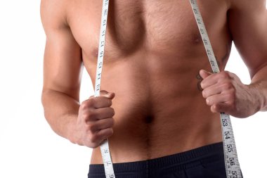 Ölçme bandı olan kaslı genç adam. Sporcu izole beyaz arka plan üzerinde ölçü tutar. Spor ve sağlıklı konsept
