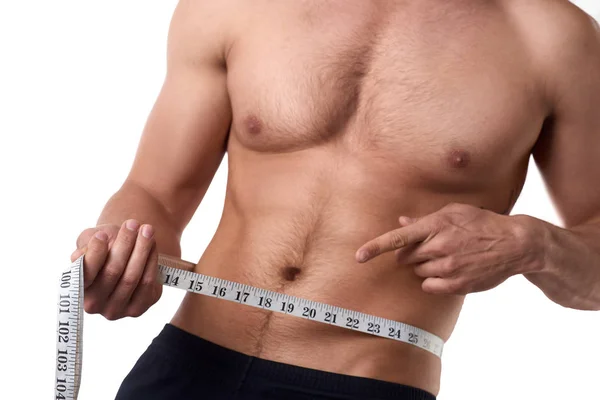 Hombre con un cuerpo musculoso midiendo sus abdominales. Hombre musculoso fuerte sobre fondo aislado — Foto de Stock