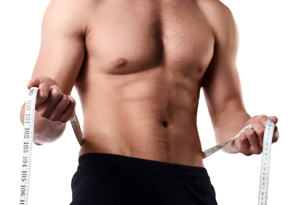 Hombre con un cuerpo musculoso midiendo sus abdominales. Hombre musculoso fuerte sobre fondo aislado — Foto de Stock