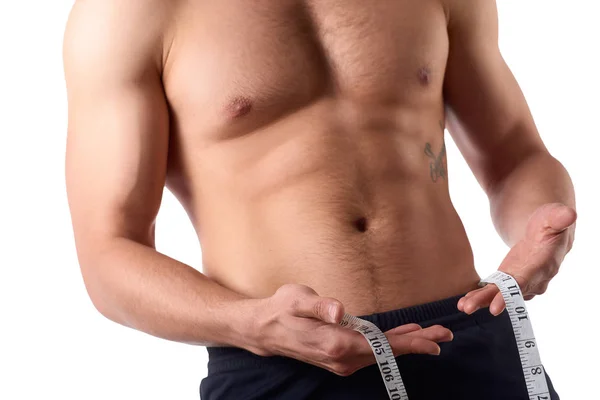 Hombre con un cuerpo musculoso midiendo sus abdominales. Hombre musculoso fuerte sobre fondo aislado — Foto de Stock