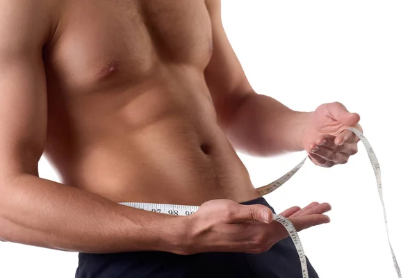 Hombre con un cuerpo musculoso midiendo sus abdominales. Hombre musculoso fuerte sobre fondo aislado — Foto de Stock