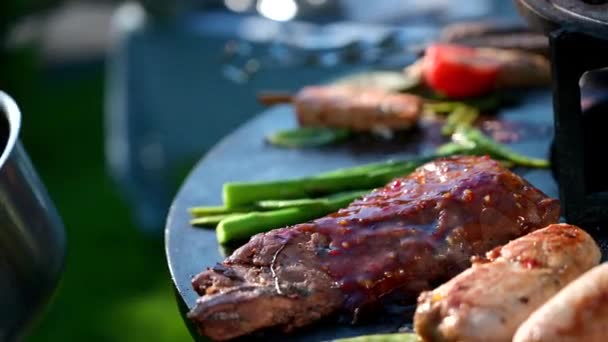 Cocine en guantes de nitrilo negro espolvorea salsa en una carne de barbacoa, carne de res en llamas, cerdo para una cena festiva, un aperitivo para la cena — Vídeos de Stock