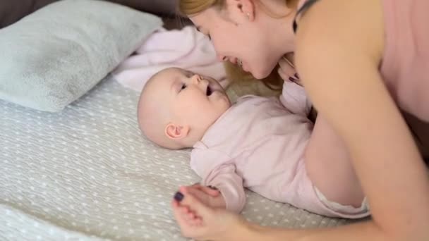 Jeune mère heureuse jouant câlins et baisers petit bébé, parent avec enfant à la maison relaxant sur le lit. Concept de famille — Video