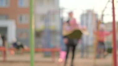Bulanık arkaplan, seçici odaklanma. Anne çocuğunu salıncakta sallıyor.