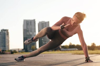 Yan kalas fitness egzersizi. Atletik kadın gün batımında dışarıda güç antrenmanı yapıyor. Spor, eğlence ve motivasyon kavramı.