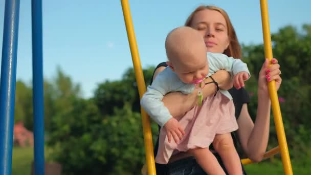 Happy mother and daughter swinging at the park. Childhood and family concept — Stock Video