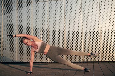 Yan kalas fitness egzersizi. Atletik kadın gün batımında dışarıda güç antrenmanı yapıyor. Spor, eğlence ve motivasyon kavramı.