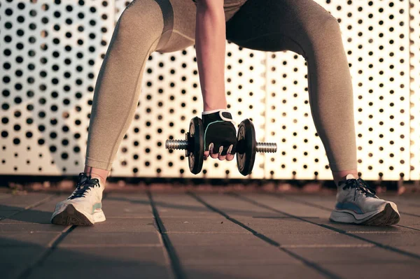 Beyaz kaslı güçlü kadın bina duvarının önünde halterle fiziksel egzersiz yapıyor. Spor fitness konsepti