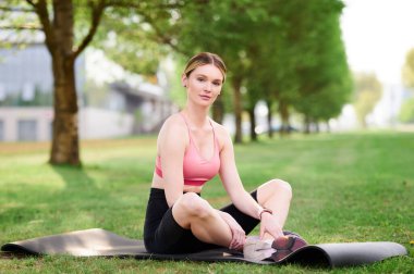 Kadın antrenmandan sonra dinleniyor. Şehir parkında yoga minderinde bir kadın.