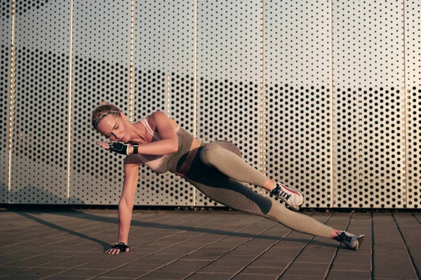 Side plank Fitness oefening. Atletische vrouw doet krachttraining buiten bij zonsondergang. Begrip sport, recreatie en motivatie. — Stockfoto