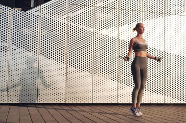 Enerjik fitness güçlü kadın ip atlama ile atlama. Sportif kız dışarıda çalışıyor.