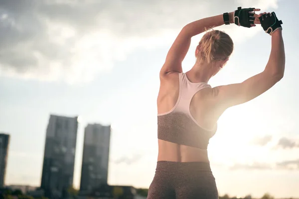 Rückseite Fitness-Frau macht Stretching-Übung im Freien, sportlich starkes Mädchen in Sportbekleidung nach dem Training vor Stadtblick — Stockfoto