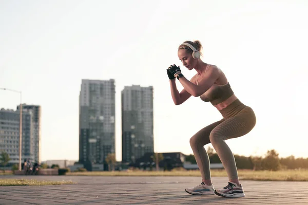 Starke Athletische Frau Macht Kniebeugen Freien Und Hört Musik Über — Stockfoto