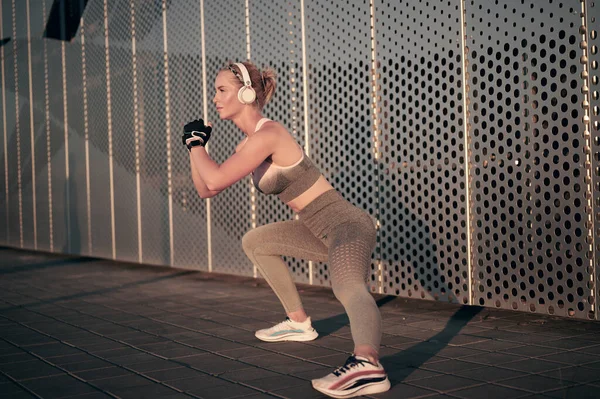 Güçlü fitness kadını dışarıda mekik çekiyor. Kulaklık takan sporcu kız egzersiz yapıyor. sağlıklı yaşam tarzı, motivasyon kavramı