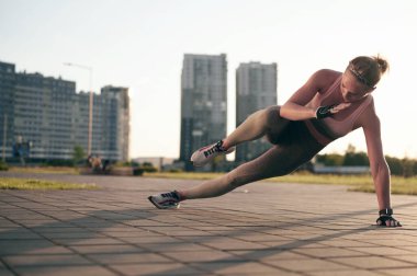 Yan kalas fitness egzersizi. Atletik kadın gün batımında dışarıda güç antrenmanı yapıyor. Spor, eğlence ve motivasyon kavramı.