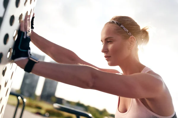 Junges muskulöses Mädchen in Sportbekleidung beim Stretching im Freien. Fitness-Frau nach dem Training, Hintergrundbeleuchtung, Stadtblick — Stockfoto