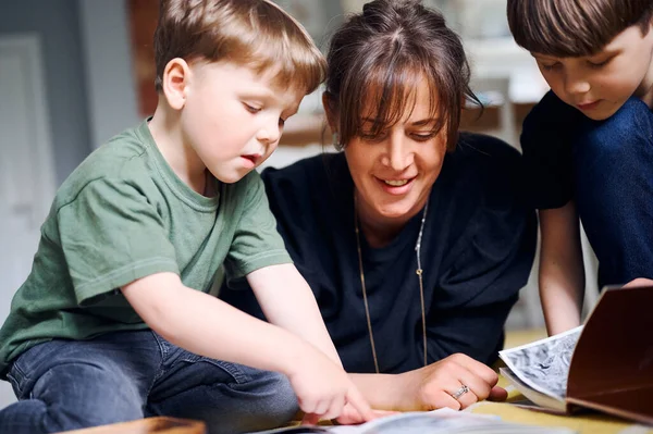 Jeune mère caucasienne passant du temps à la maison avec des fils et lisant des livres sur le sol. Joyeux parent jouant avec des enfants d'âge préscolaire. Concept d'enseignement à domicile — Photo