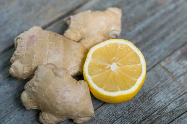 Gri ahşap arka planda limonlu taze zencefil kökü