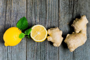 Taze zencefil kökü ve limon ve nane ya da eski gri ahşap arka planda mellis yaprakları. Üst görünüm, düz görünüm, kopyalama alanı