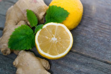Taze zencefil kökü ve limon ve nane veya eski gri ahşap arka planda mellis yaprakları.