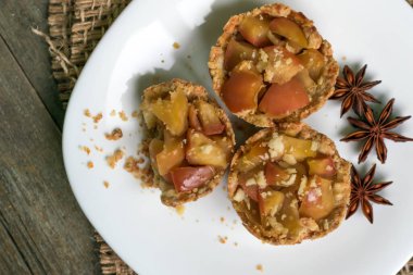 Elmalı kısa hamurlu hamur tatlısı, anason ve tarçınlı ev yapımı tatlılar. Manzaralı, ahşap bir arka planda topçu. Doğal çevre tatlısı konsepti, sıcak sıcak çay partisi.