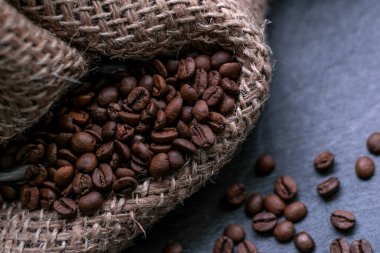 Gri bir taş kalça üzerinde fırında kahve çekirdeği ve bir çuval bezi. makro yakın çekim görünümü