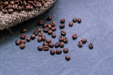 Gri taşlı bir arka planda poşette kahve çekirdekleri.