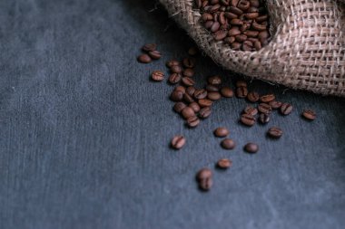 Gri taşlı bir arka planda poşette kahve çekirdekleri.