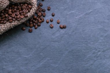 Gri taşlı bir arka planda poşette kahve çekirdekleri.