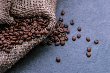 Gri bir taş kalça üzerinde fırında kahve çekirdeği ve bir çuval bezi. makro yakın çekim görünümü