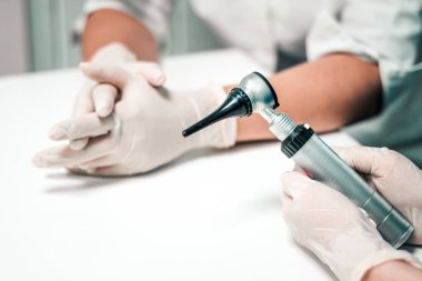 Yakın çekim otoskop laboratuardaki bir doktorun kulaklarını kontrol ediyor. Kadın laboratuvar asistanı ve veteriner doktorun elleri. Otitis medyası ve kulak hastalıkları için teşhis ekipmanları.