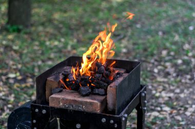 Demirhanede yangın, doğada demir ocağı, yeşil otların arka planında açık hava. ateşlenen kömür