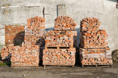 Eski gri duvar arka plan karşı ahşap palet üzerinde tuğla yığını.