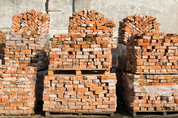 Stacks of bricks on wooden pallets in the construction site.