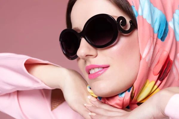 Smiling sixties style woman with scarf and sunglasses.