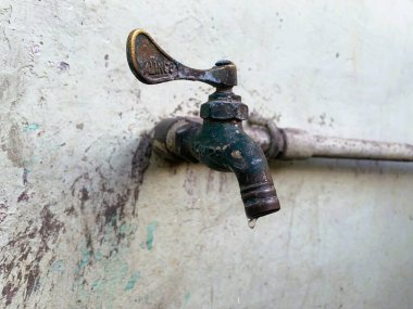 Fakir bir tesisat sisteminden sızan paslı bir musluk değerli suyu boşa harcıyor ve sürdürülebilirliği baltalayan bir sorunu vurguluyor.