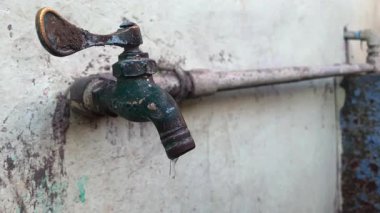 Fakir bir tesisat sisteminden sızan paslı bir musluk değerli suyu boşa harcıyor ve sürdürülebilirliği baltalayan bir sorunu vurguluyor.