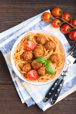 İtalyan asıllı ABD'li geleneksel saçmak spagetti köfte, domates sosu ve fesleğen kase, çatal ve peçete, rustik ahşap arka plan, üstten görünüm. Yakın çekim köfte geçmiş