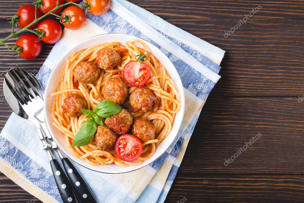 Italian American traditional dish spaghetti with meatballs, tomato sauce and basil in bowl, rustic wooden background, top view, copy space. Close-up of meatballs past