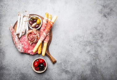 Soğuk et kesim ve mezeler, prosciutto, jamon, salam dilimleri, sosis, grisini, zeytin çeşididir. Çeşitli rustik ahşap masa, metin, üstten görünüm, yakın-u alan üzerinde et karışımı