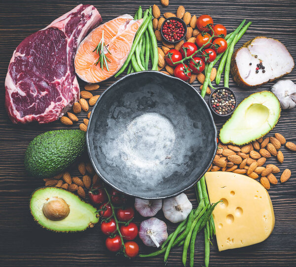 Empty rustic bowl with low carbs ingredients for clean eating and weight loss, copy space, top view. Keto foods: meat, fish, avocado, cheese, vegetables, nuts. Ketogenic diet concept, healthy fats