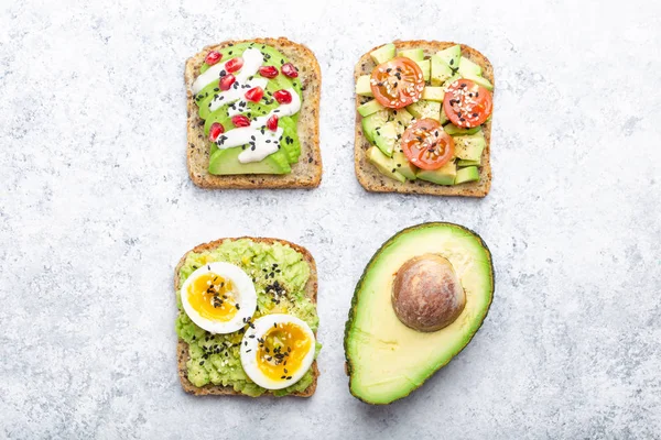 Yumurta, domates, baharat ve beyaz taş zemin üzerine bütün avokado Yarım avokado tost. Sağlıklı kahvaltı avokado sandviç farklı soslar, üstten görünüm, yakın-u